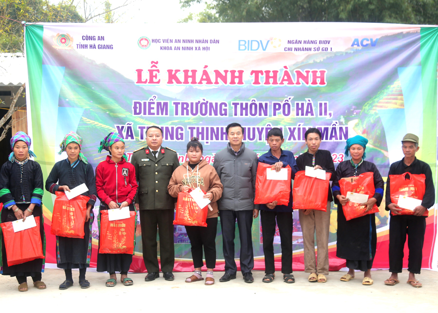 Giám đốc Công an tỉnh và lãnh đạo huyện Xín Mần tặng quà Tết cho các hộ nghèo xã Trung Thịnh.
