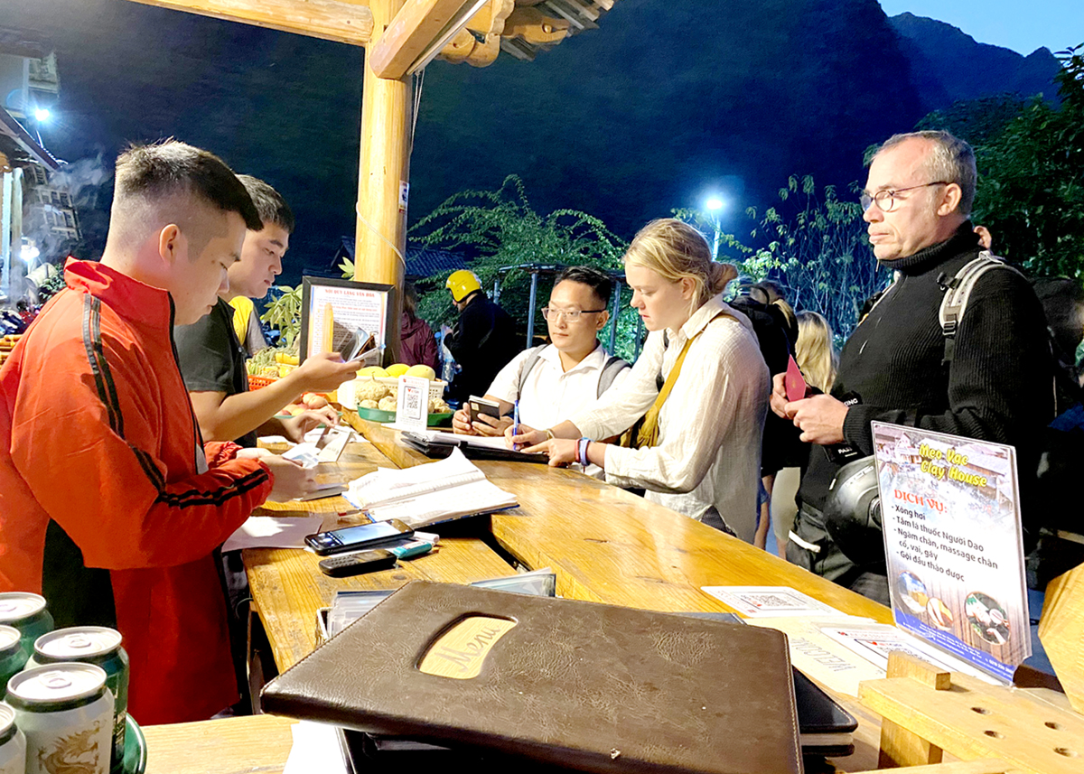 Du khách nước ngoài thanh toán không dùng tiền mặt tại Làng Văn hóa du lịch cộng đồng thôn Pả Vi Hạ, xã Pả Vi.

