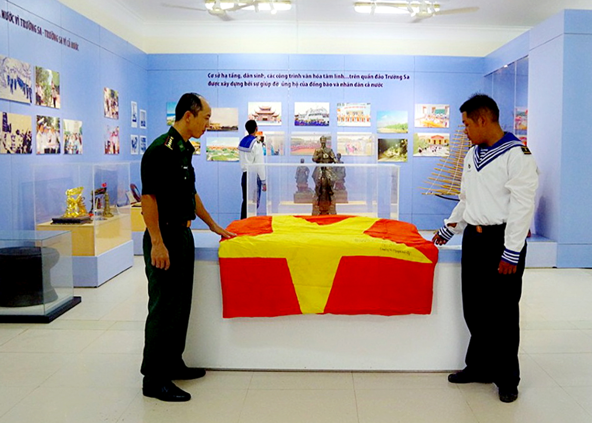 Lá cờ 54 m2 đã treo ở Cột cờ Lũng Cú do Đoàn công tác của tỉnh Hà Giang tặng Đảo trường Sa (tháng 5.2012) được lưu giữ tại Nhà truyền thống của Đảo. 											Ảnh: Hồ Quang Sinh (Vùng 4 Hải quân).