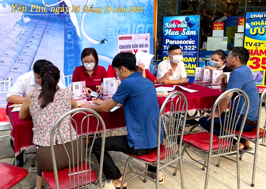 Cán bộ Agribank Bắc Mê tuyên truyền, hướng dẫn người dân thanh toán không dùng tiền mặt tại thị trấn Yên Phú.
