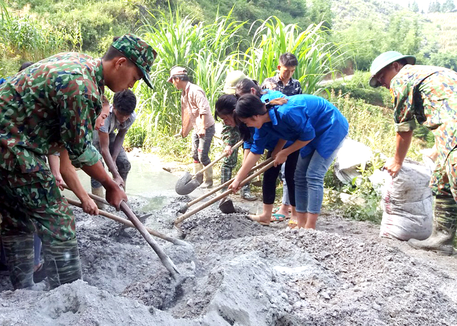 Cán bộ, chiến sỹ Đồn Biên phòng Sơn Vĩ (Mèo Vạc) hỗ trợ người dân tu sửa đường bê tông. 