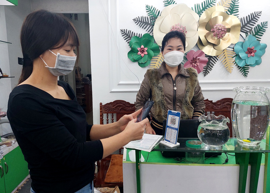 Người dân thanh toán hóa đơn tại cửa hàng Eva shose, đường Nguyễn Thái Học, phường Minh Khai (thành phố Hà Giang) thông qua quét mã QR ngân hàng.