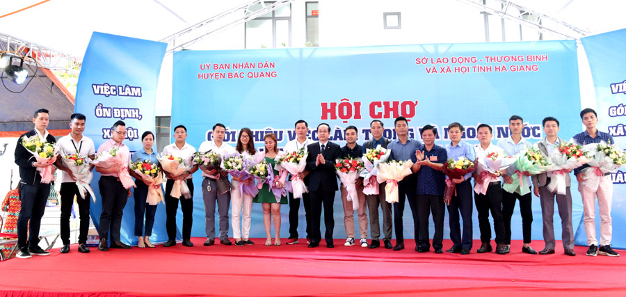Lãnh đạo huyện Bắc Quang, Sở Lao động – Thương binh và Xã hội tặng hoa cho các doanh nghiệp, đơn tuyển dụng lao động tham gia hội chợ.