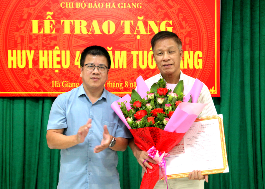 Bí thư Chi bộ Báo Hà Giang Nguyễn Trung Thu trao quyết định, tặng hoa chúc mừng đồng chí Lê Trọng Lập.
