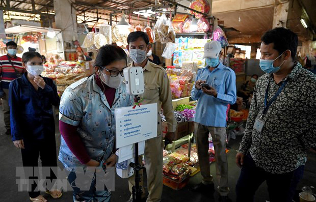 Người dân kiểm tra thân nhiệt trước khi vào chợ để phòng chống dịch COVID-19 tại Lào. 