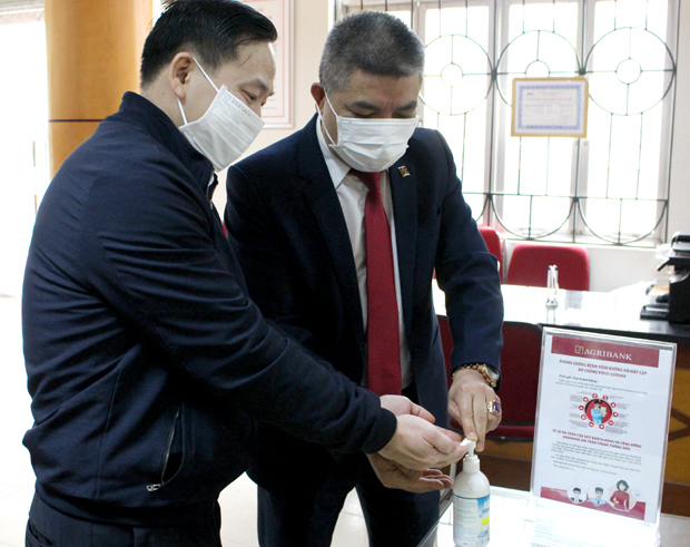 Cán bộ Agribank Hà Giang hướng dẫn khách hàng rửa tay sát khuẩn trước khi giao dịch.                                                             Ảnh: L.L