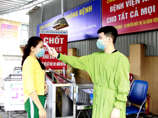 Người dân đến khám bệnh tại Bệnh viện Đa khoa Đức Minh (thành phố Hà Giang) được đo thân nhiệt, sát khuẩn tay, đeo khẩu trang và khai báo y tế đầy đủ.                                             Ảnh: BIỆN LUÂN