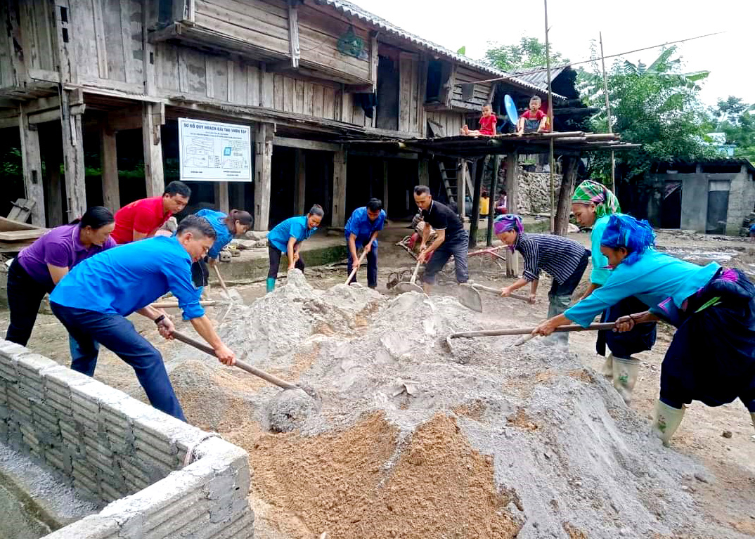 Cán bộ MTTQ và nhân dân giúp đỡ gia đình liệt sỹ tại xã Sán Sả Hồ đổ nền sân xi măng.
