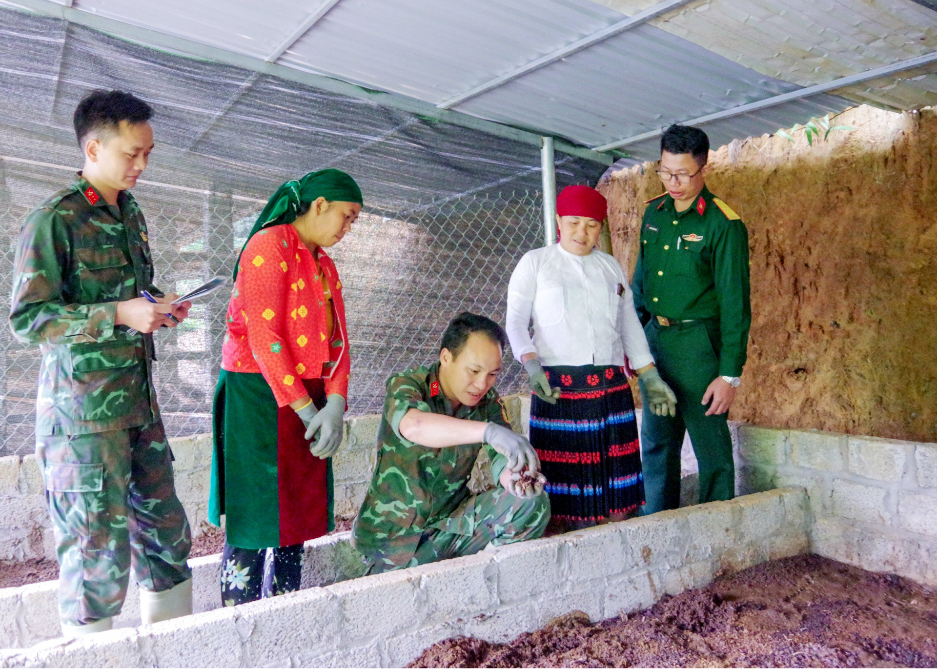 Cán bộ, nhân viên Đoàn Kinh tế - Quốc phòng 313 hướng dẫn người dân địa phương cách nuôi giun quế.
