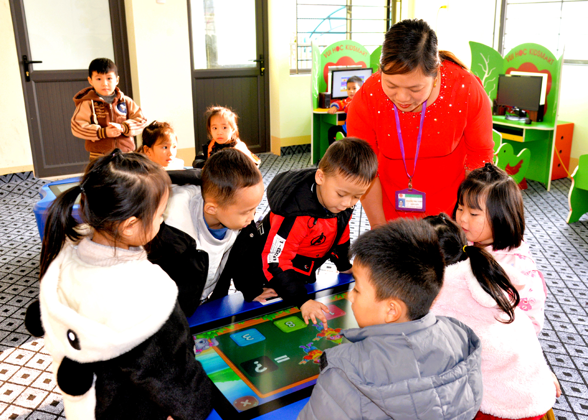 Cô giáo Trường Mầm non Sao Mai hướng dẫn các em học sinh học tập trong phòng học thông minh.