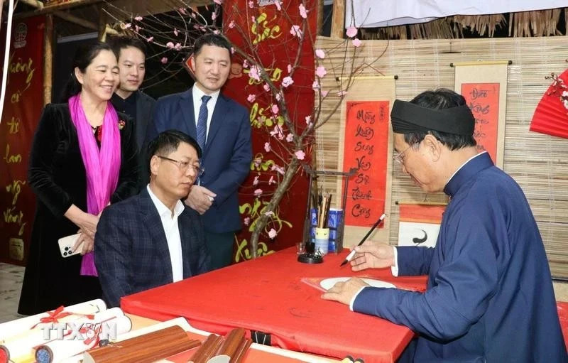 Tourists ask for a calligraphy at a stall in the traditional Tet market in Hoa Lu old quarter. 