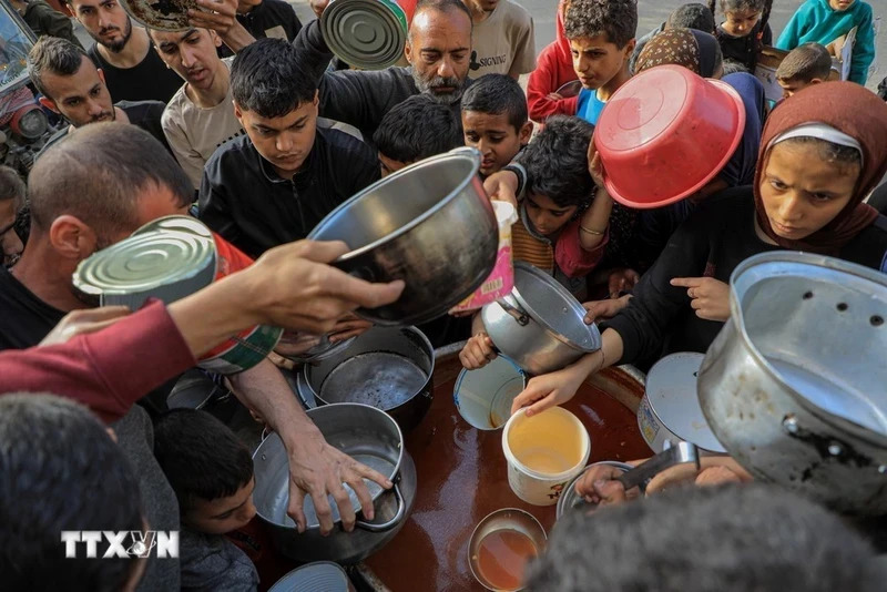 People wait to receive food aid in Rafah City, southern Gaza Strip on March 30, 2024.