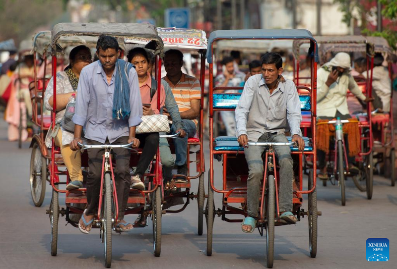 People ride rickshaws at a market place in New Delhi, India, on April 26, 2023.