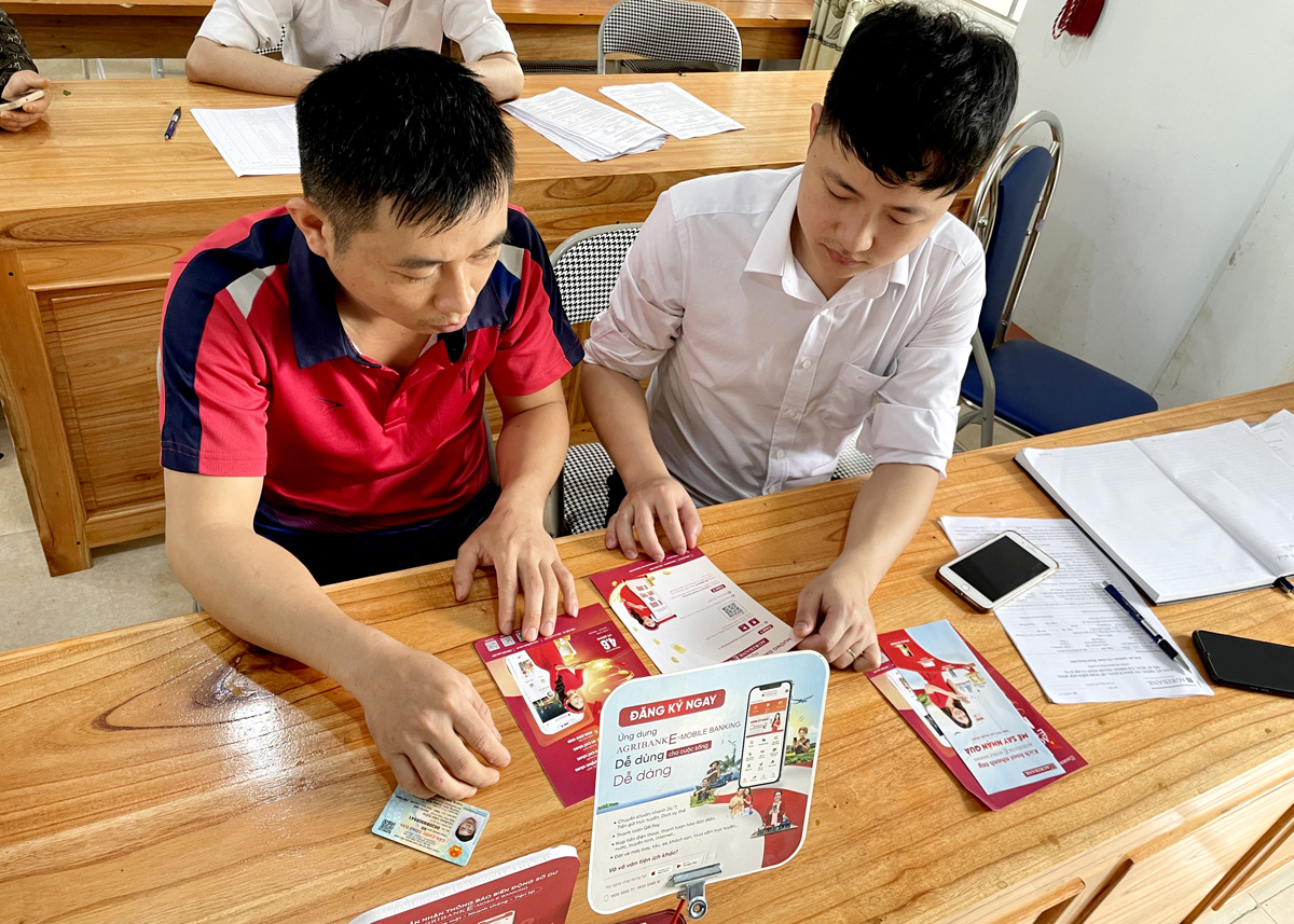 Cán bộ Agribank Quang Bình tuyên truyền, hỗ trợ người dân sử dụng dịch vụ ngân hàng.