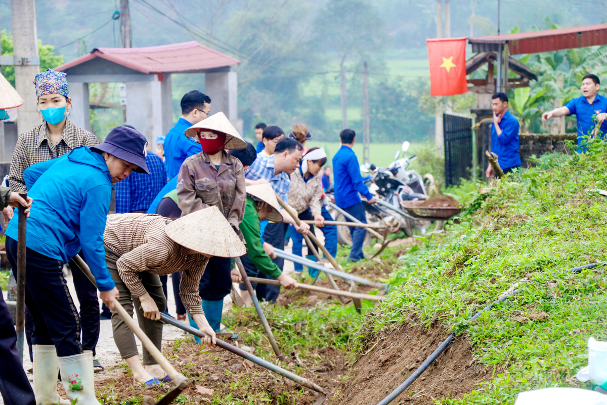 Đoàn viên, thanh niên và người dân xã Tân Trịnh (Quang Bình) tham gia đắp lề đường bê tông thôn Mác Hạ. Ảnh: Trung Hậu.