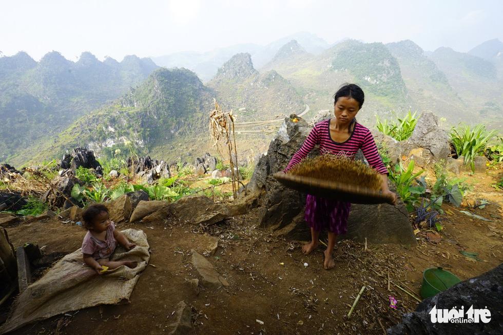 A woman does household chores while her child sits nearby in Dong Van District, Ha Giang Province, Vietnam. Photo: Quang Dinh / Tuoi Tre