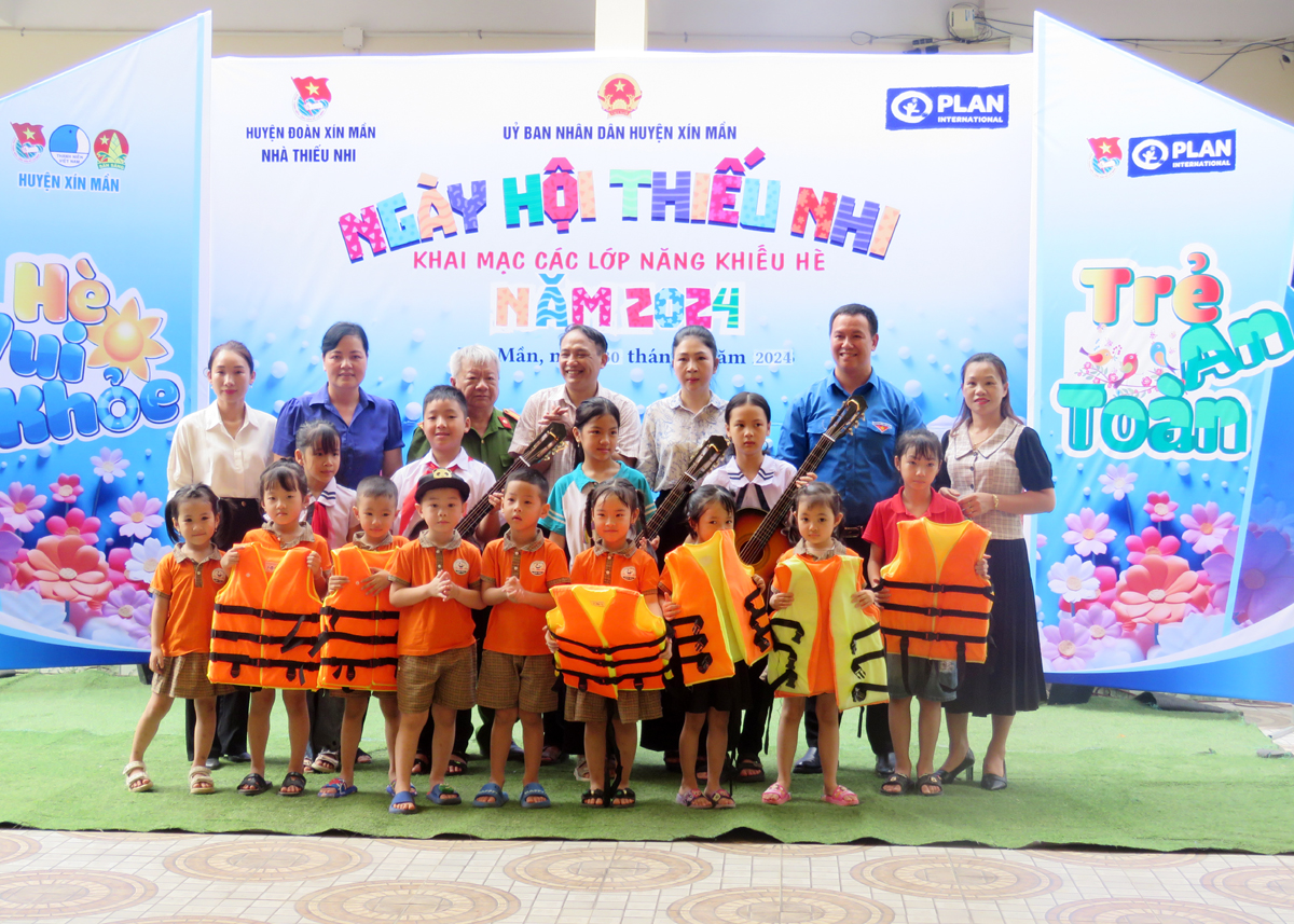Lãnh đạo UBND huyện Xín Mần và tổ chức Plan tại Hà Giang tặng quà cho các em thiếu nhi.