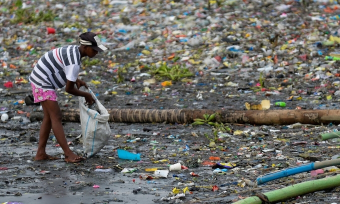 A woman picks up plastic cups along the riverbank of Pasig river, in Manila, Philippines, June 10, 2021. Photo by Reuters