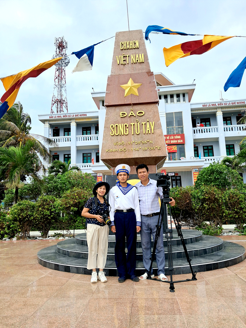 Chiến sỹ Phan Tuấn Anh chụp ảnh với các nhà báo tỉnh Hà Giang bên cột mốc chủ quyền tại đảo Song Tử Tây.