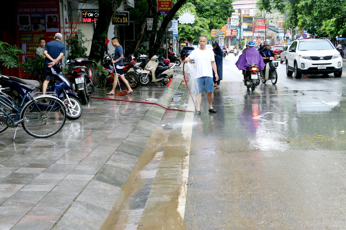 Người dân dùng vòi nước để xịt bùn làm sạch đường phố

