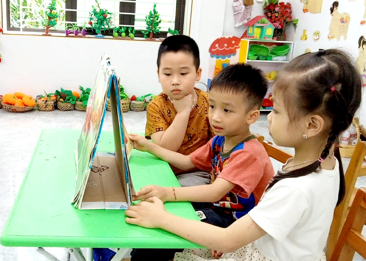 Một học sinh lớp 5 tuổi (bé ngồi giữa), Trường Mầm non Kim Thạch, Vị Xuyên đã biết đọc truyện tranh.