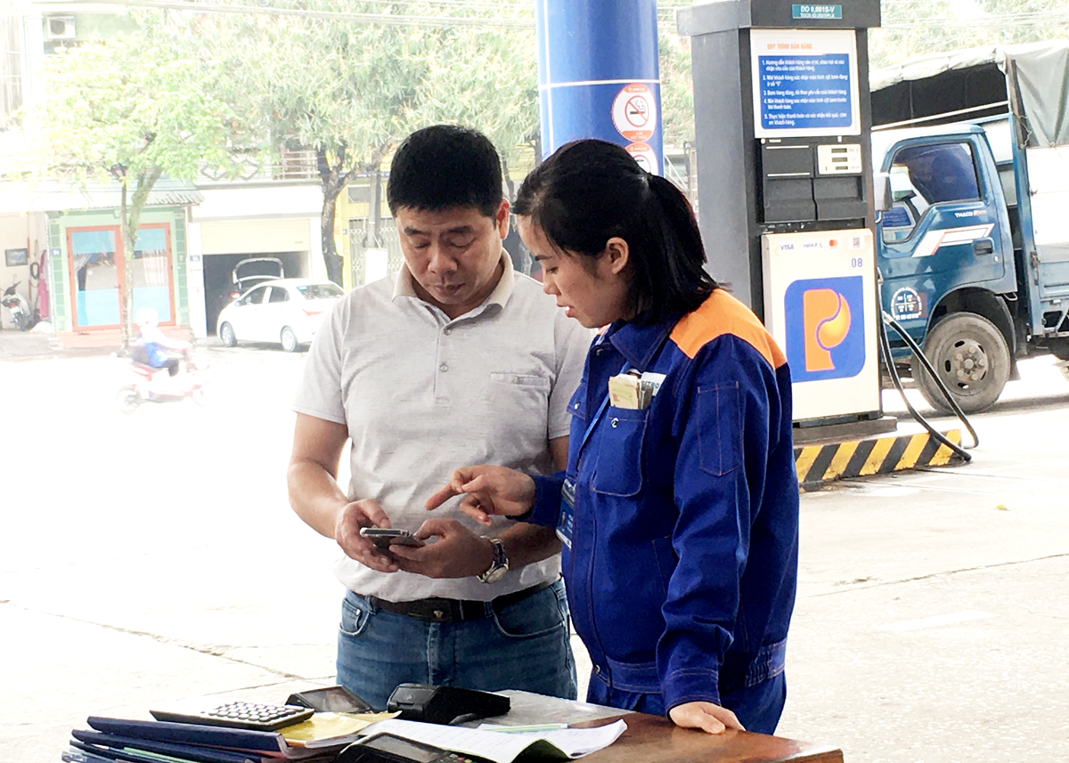 Nhân viên Công ty Xăng dầu Hà Giang hướng dẫn khách hàng thanh toán không dùng tiền mặt. 