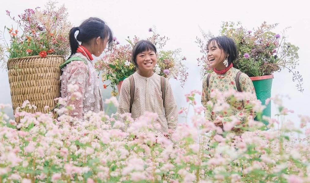 Ethnic minority kids carry a basket full of buckwheat flowers on their backs.