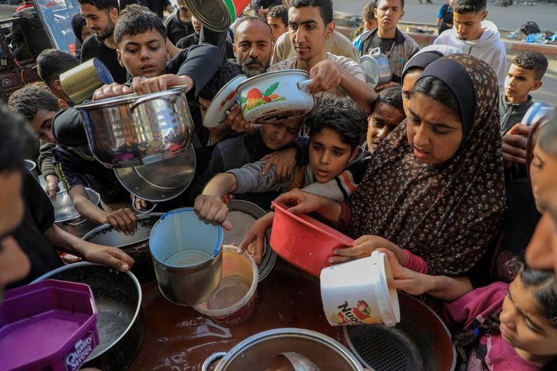 People wait to receive food relief in the southern Gaza Strip city of Rafah, on March 30, 2024. 