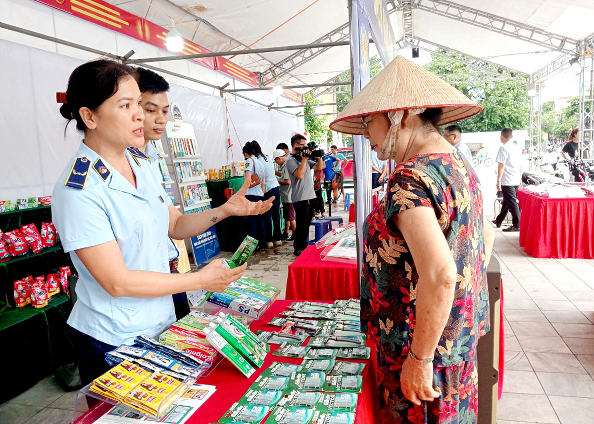 Kiểm soát viên Cục Quản lý thị trường tỉnh hướng dẫn người tiêu dùng phân biệt hàng thật, hàng giả.
