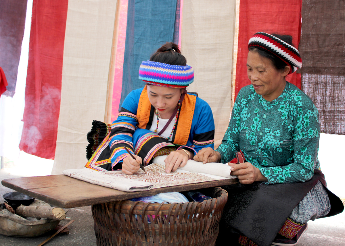 Teaching beeswax drawing on fabric to the younger generation.