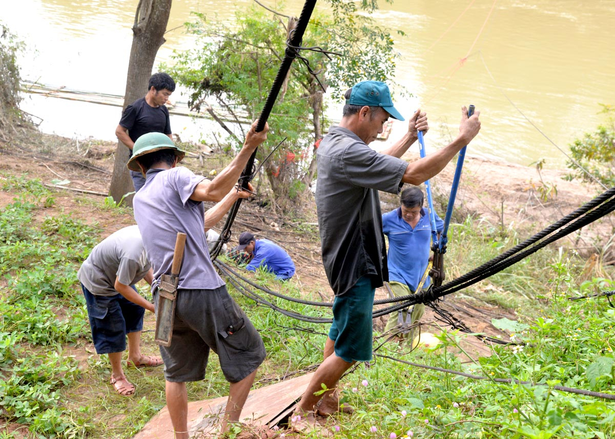 Người dân thôn Tân Bình, thị trấn Yên Bình thu gom những thanh sắt còn lại của cây cầu treo đã bị lũ cuốn trôi.