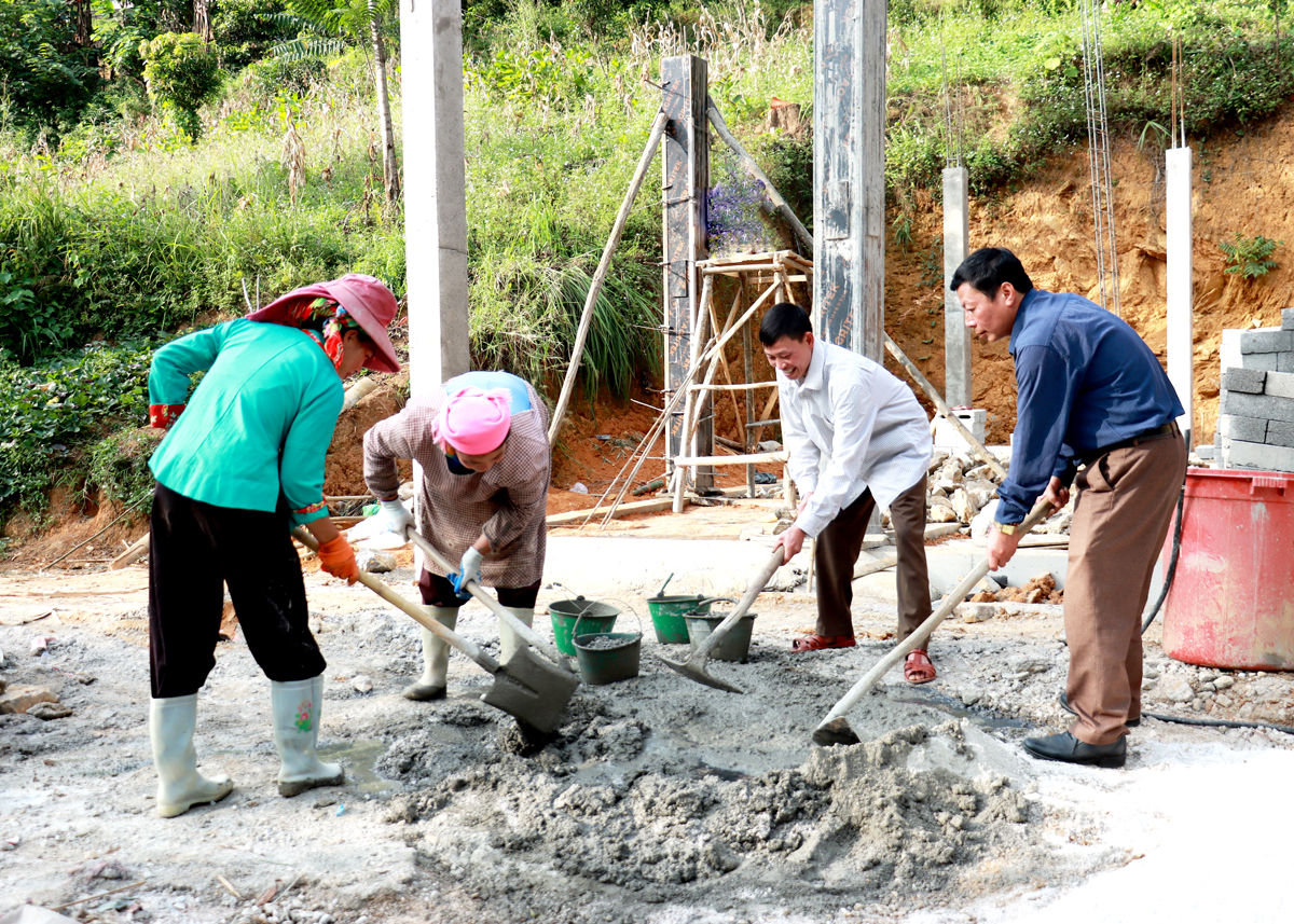 Cán bộ xã Xín Cái giúp hộ nghèo thôn Bản Trang xây dựng nhà ở.

