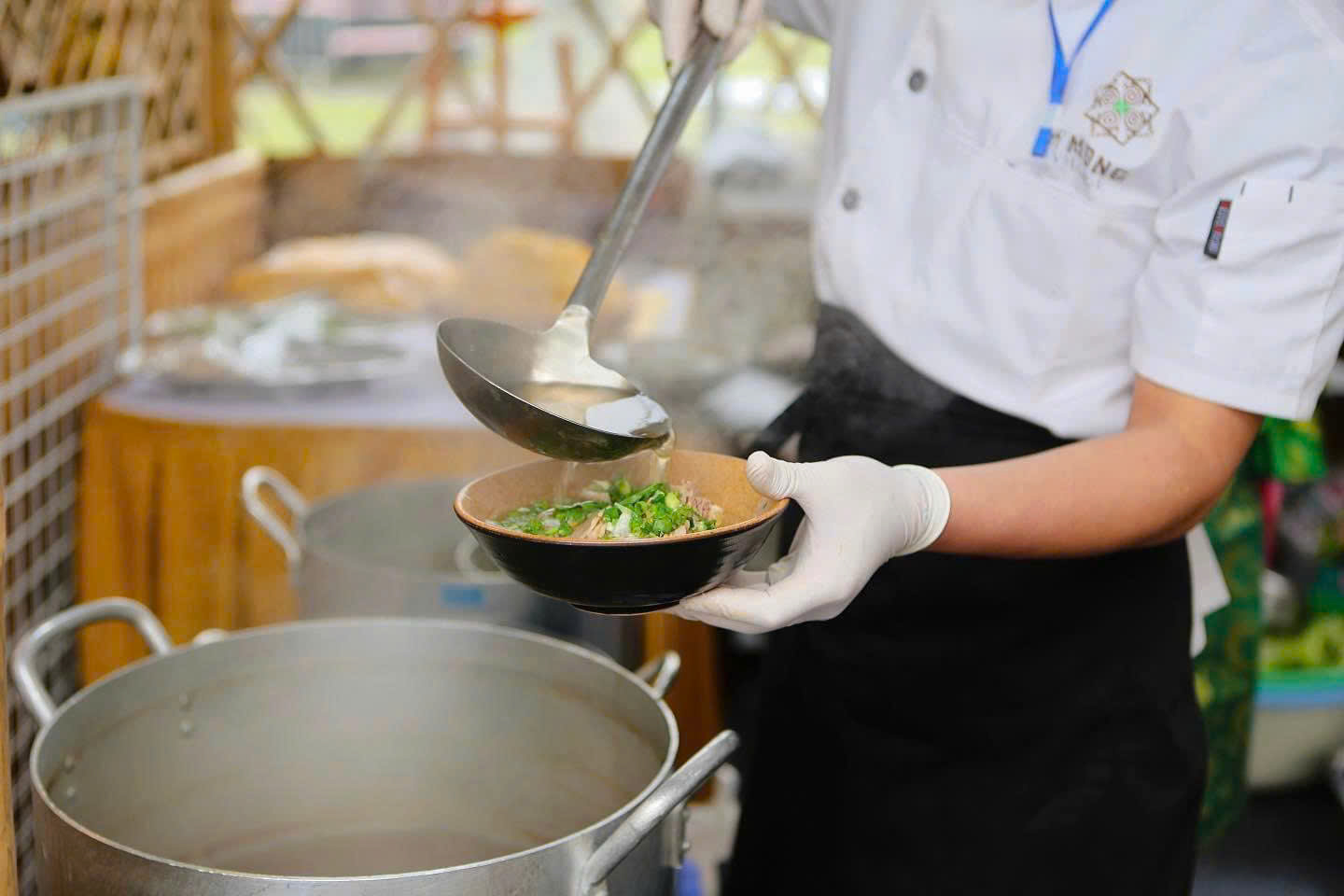 Pho Ngo noodles are placed in a bowl, topped with beef and spring onions, and finished with steaming hot beef broth to cook the meat and release the sweet corn flavour hidden in the noodles.