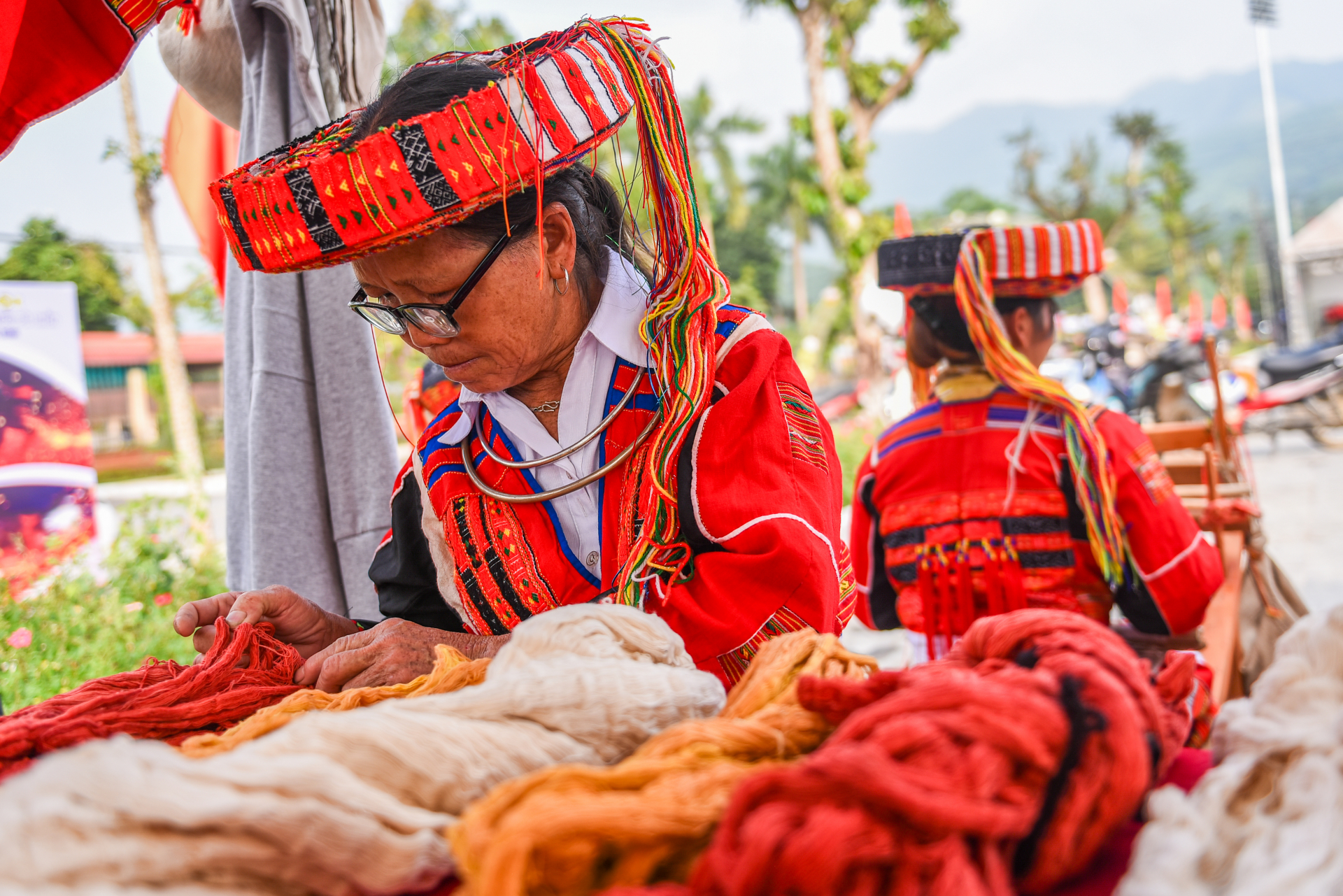 Artisan Tan Thi Lo (59 years old, Ha Son Village Cooperative) is one of 12 craftsmen demonstrating embroidery and weaving techniques on-site. The weaving frames depict the journey of turning threads into brocade fabrics adorned with special motifs.