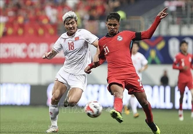 Thanh Binh (whites dribbling is fiercely blocked by a Singaporean defender at the first leg of the ASEAN Cup semifinal on December 26.