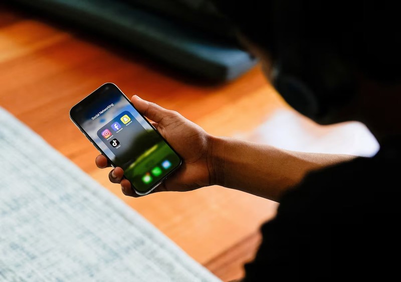 A high school student poses with his mobile phone showing his social media applications in Melbourne, Australia, November 28, 2024.