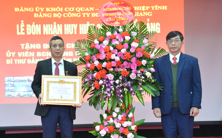 Bí thư Đảng ủy khối cơ quan, doanh nghiệp tỉnh trao Huy hiệu 30 năm tuổi Đảng và tặng hoa chúc mừng đồng chí Hoàng Văn Thiện.