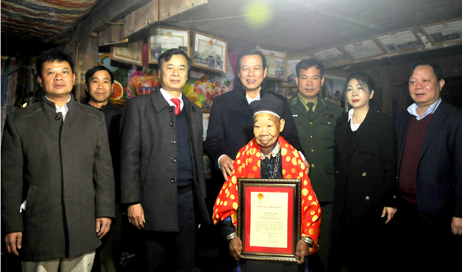 Chủ tịch UBND tỉnh Nguyễn Văn Sơn trao thiệp mừng và vải lụa cho cụ bà Vàng Già Ngấn, thôn Na Pan, thị trấn Cốc Pài.